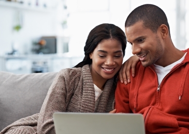young couple on couch looking at laptop computer